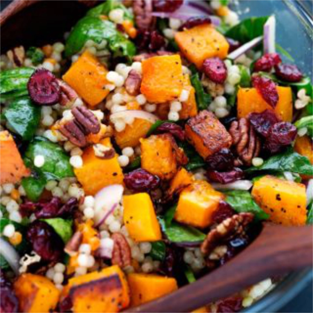 Close up of cubed butternut squash with a mixture of dried fruit and spinach