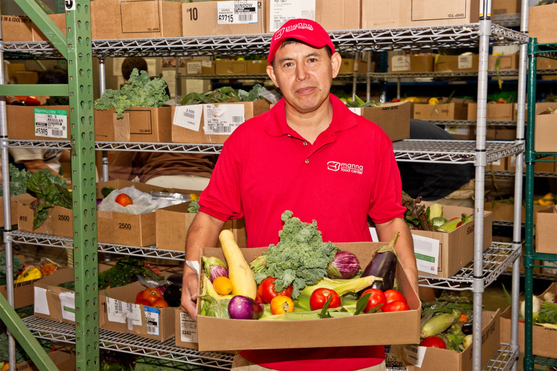 Manna staff holding up box of fresh fruits and vegetables at warehouse