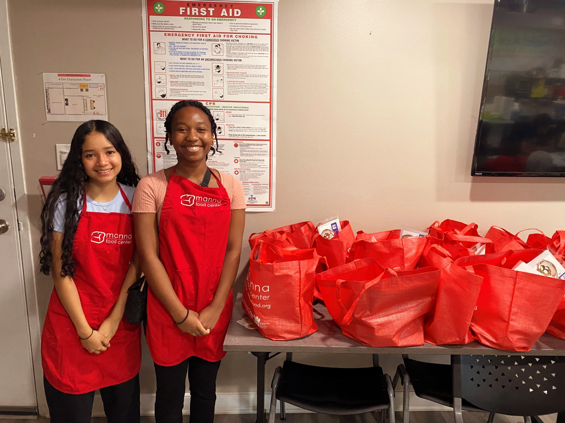 School-aged children in Manna aprons smiling with bags of of food donations
