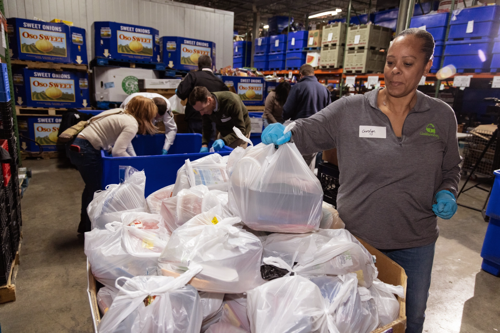Volunteer arranging finished food donation bags at warehouse