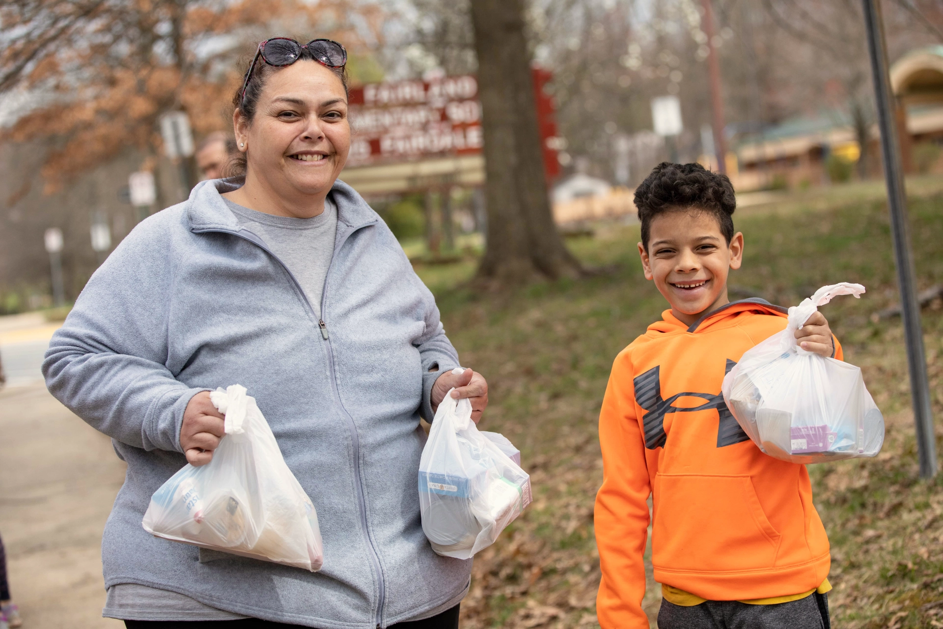 Woman and young son smiling with bags of donated food