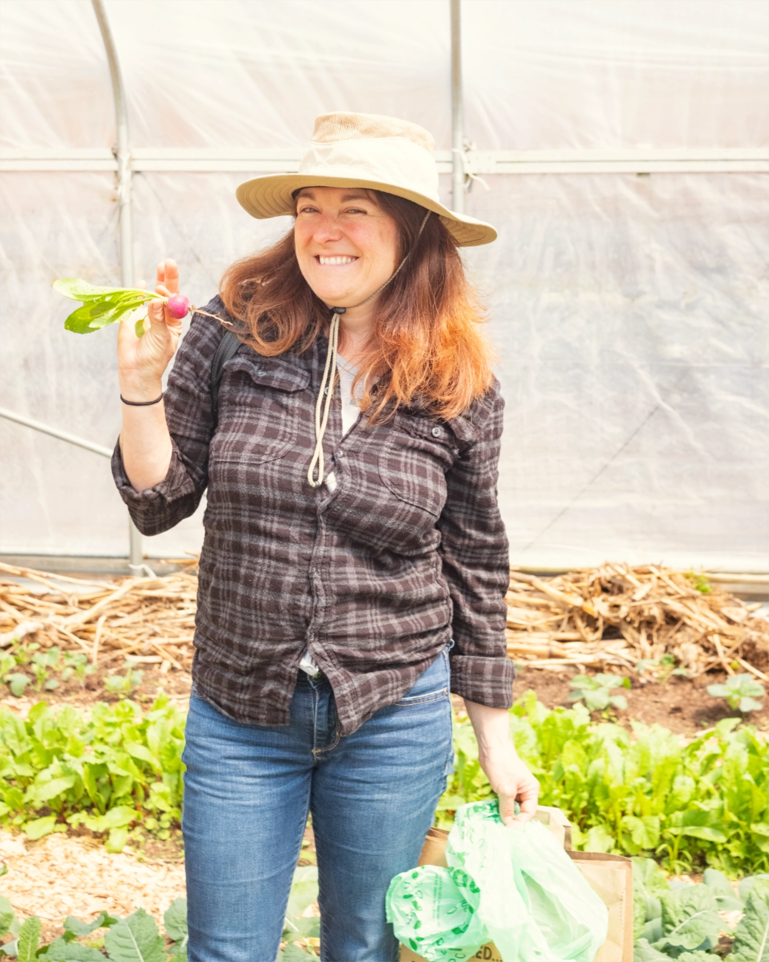 Woman holding up freshly picked radish in greenhouse