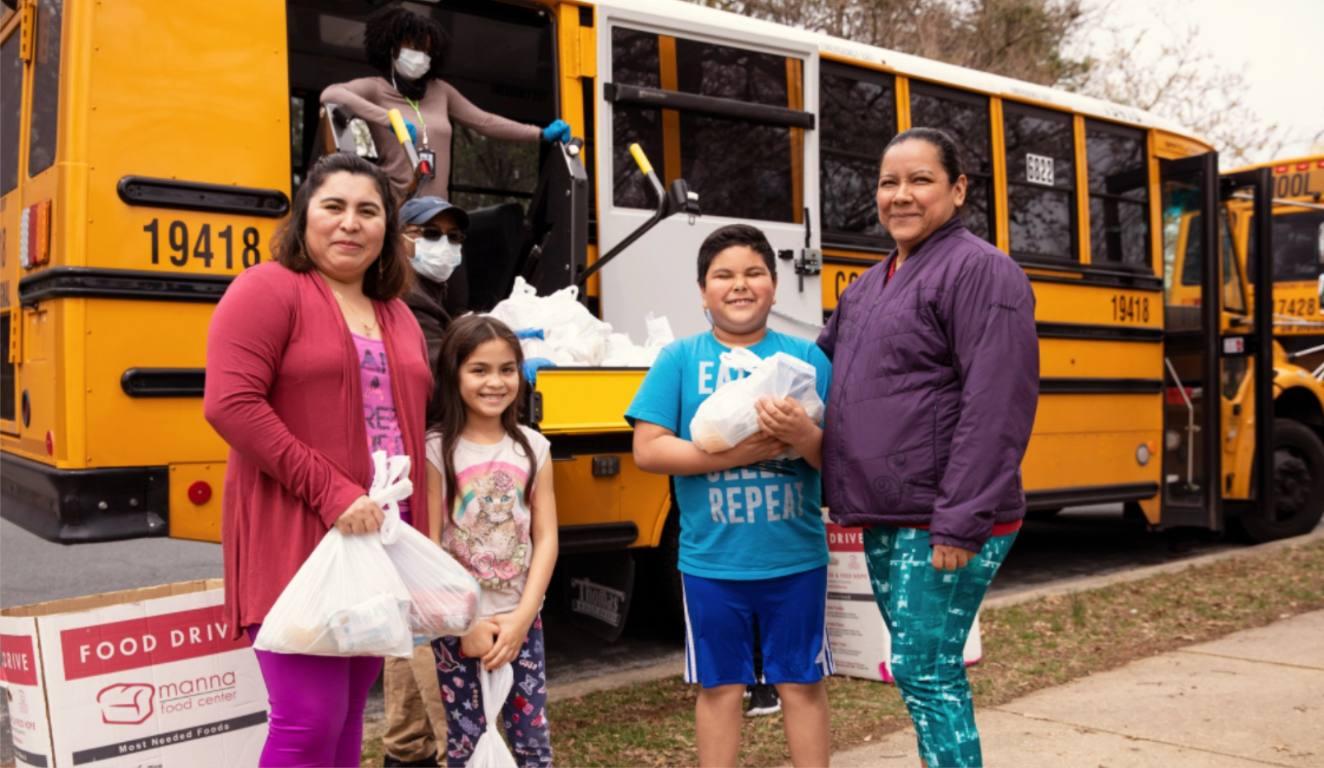Mujeres y niños con alimentos de la distribución del autobús escolar